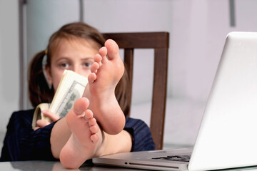 Humorous portrait of happy cute young business girl counts money profit with bare feet on the...