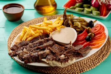 Turkish meat Shawarma Plate with fries, mayo dip, sauce, salad served in a dish isolated on cutting board side view