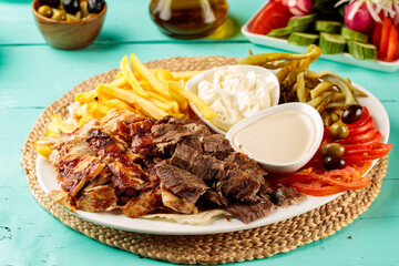 Turkish Mixed meat Shawarma Plate with fries, mayo dip, sauce, salad served in a dish isolated on cutting board side view