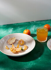 food, healthy eating and fruits concept - still life with peeled mandarins on plate and glass of...