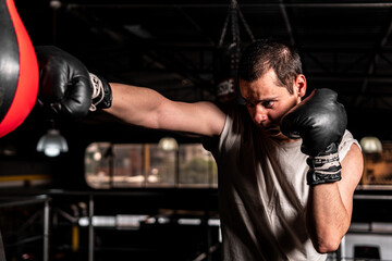 High quality photography. Caucasian boxer with gloves on hitting a boxing pear. Slim man practicing...