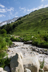 Mountain river Terskol in a picturesque valley among the green slopes of the mountains on a sunny summer day in the Elbrus region Russia