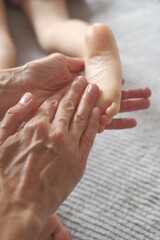 Fototapeta premium Masseur hands gives foot massage to a child. Sensual touching 