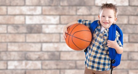 Smiling boy holding a basketball ball and posing