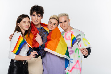 stylish different identity friends with lgbtq flags smiling at camera isolated on grey.