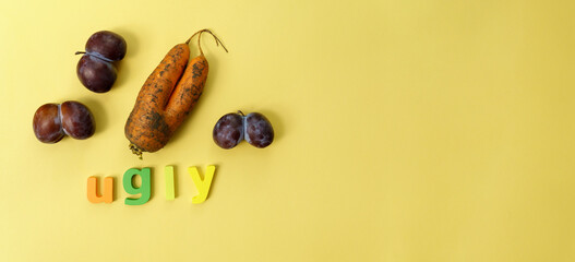 Ugly plums and carrot on yellow background. fruits are suitable for food. Concept Reduction of...