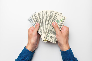 a man's hand in a shirt holds a bunch, a fan of dollar bills, money