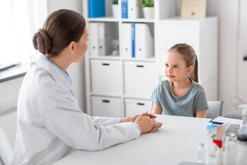 Obraz premium medicine, healthcare and pediatry concept - female doctor or pediatrician talking to little girl patient on medical exam at clinic