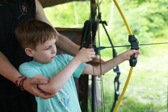 Instructor teaching boy to shoot bow