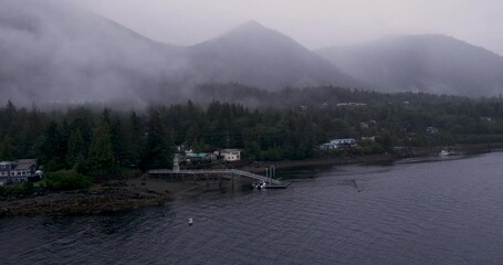 Passing house, private docks and pine trees sailing while sailing through the Tongass Narrows into the southeast Alaska town of Ketchikan