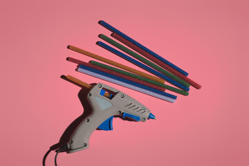 hot gun and glue shiny sticks on a colored background