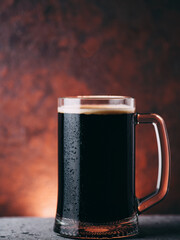 A mug of dark draft beer. Close-up on a brown background