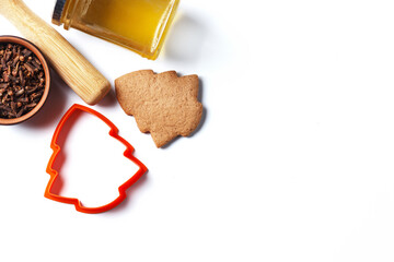 Ready-made Christmas cookies in the form of a Christmas tree with a cookie mold and ingredients: honey, cloves isolated on a white background. copy space.
