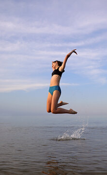 young girl jumps very high to manifest joy and enthusiasm by the sea