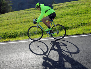young cyclist with racing bicycle and phosphorescent waterproof jacket on the road