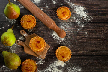 Rustic tarts amidst a baking scene with fresh pears on the side, suggesting the use of natural ingredients for a homemade treat