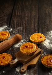 Warm, freshly baked tarts dusted with sugar, displayed on a rustic wooden board, evoking homey comfort and sweetness