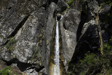 A small but beautiful waterfall falling straight from a rocky mountain. A perfect summer landscape found during har ki dun valley trek in the state of Uttarakhand in India.