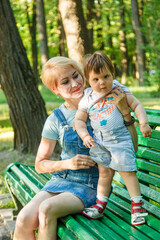 beautiful girl with children sits on a bench in the park