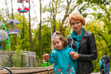 Fototapeta na wymiar beautiful girl (mother) with a girl (daughter) in the park in the park are sitting on a bench