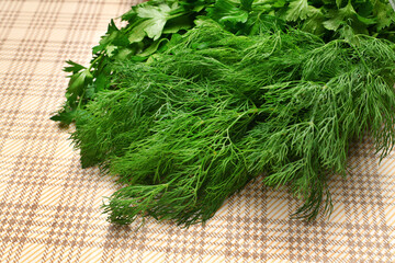 a bunch of green dill and parsley on a rustic checkered table cloth, concept of fresh vegetables and healthy food
