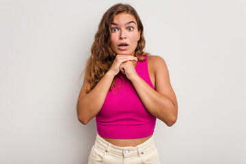 Young caucasian woman isolated on blue background praying for luck, amazed and opening mouth looking to front.