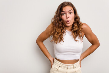 Young caucasian woman isolated on blue background being shocked because of something she has seen.