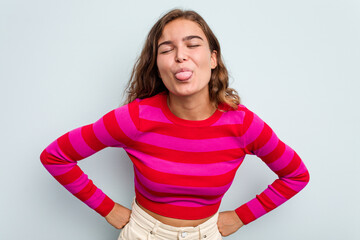 Young caucasian woman isolated on blue background funny and friendly sticking out tongue.