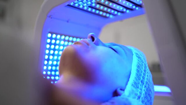 Close up of young woman having red and blue LED light facial therapy treatment in beauty salon. A non-invasive type of phototherapy. Beauty, healthcare and wellness concept. Cosmetology and Skin Care