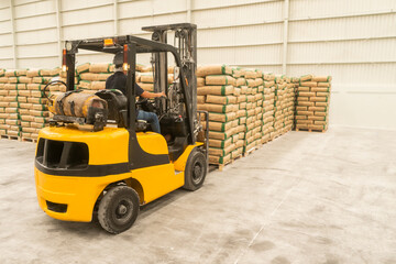Hispanic operator driving a forklift stacking bags in an industrial plant in Latin America
