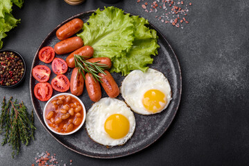 Traditional English breakfast with eggs, toast, sausages, beans, spices and herbs on a grey ceramic plate