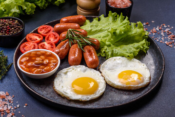 Traditional English breakfast with eggs, toast, sausages, beans, spices and herbs on a grey ceramic plate