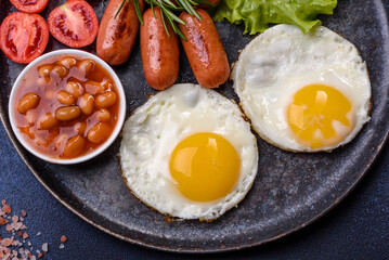Traditional English breakfast with eggs, toast, sausages, beans, spices and herbs on a grey ceramic plate