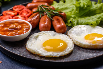 Traditional English breakfast with eggs, toast, sausages, beans, spices and herbs on a grey ceramic plate