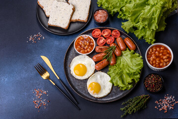 Traditional English breakfast with eggs, toast, sausages, beans, spices and herbs on a grey ceramic plate