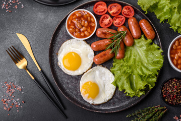 Traditional English breakfast with eggs, toast, sausages, beans, spices and herbs on a grey ceramic plate