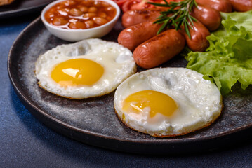 Traditional English breakfast with eggs, toast, sausages, beans, spices and herbs on a grey ceramic plate