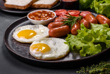 Traditional English breakfast with eggs, toast, sausages, beans, spices and herbs on a grey ceramic plate