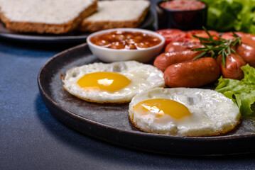 Traditional English breakfast with eggs, toast, sausages, beans, spices and herbs on a grey ceramic plate