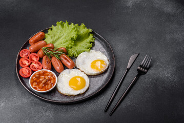 Traditional English breakfast with eggs, toast, sausages, beans, spices and herbs on a grey ceramic plate