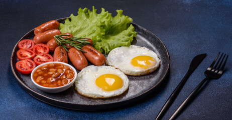 Traditional English breakfast with eggs, toast, sausages, beans, spices and herbs on a grey ceramic plate