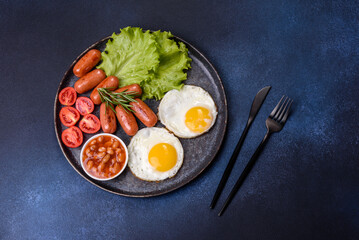 Traditional English breakfast with eggs, toast, sausages, beans, spices and herbs on a grey ceramic plate