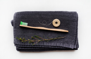 eco natural bamboo toothbrushes and biodegradable silk  dental floss on the black towel,  sustainable lifestyle concept. zero waste home. bathroom essentials, plastic free items