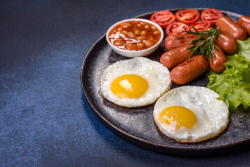 Traditional English breakfast with eggs, toast, sausages, beans, spices and herbs on a grey ceramic plate