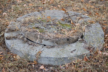 one old large gray concrete manhole on the street in the dry grass