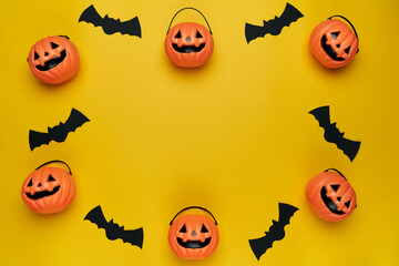 Halloween decorations with paper bats and pumpkin head baskets with yellow background