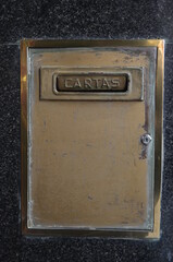 Antique golden letter box on a marble wall