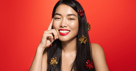 Beautiful asian woman with red lips, glowing clear skin, has smooth shiny hair with chrismas gift...