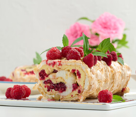 Baked meringue roll with cream and fresh red raspberry, white background