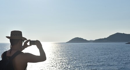 Fototapeta premium a man takes photos of the sunset on the island of Mljet with his mobile phone